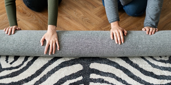 Ein Pärchen rollt einen Zebra-Teppich auf.